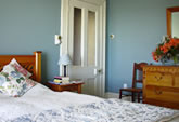 The Bedroom has chintz curtains and native rimu furniture. It has a Queen size bed and views of the Nelson Harbour. 